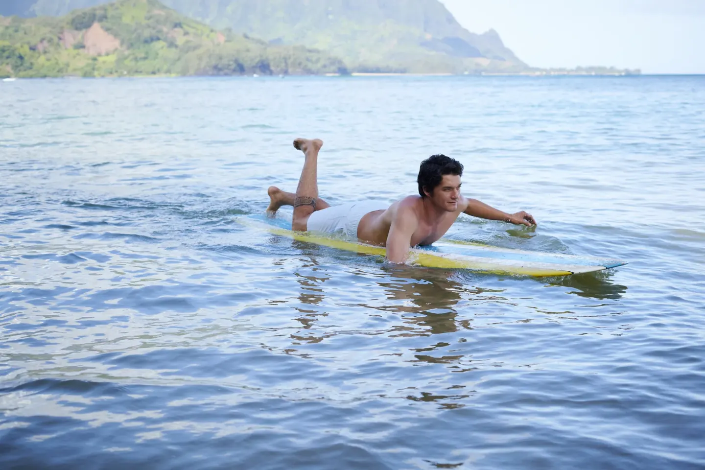 Guest paddling on a surfboard in 1 Hotel Hanalei Bay at 1 Hotel Hanalei Bay.
