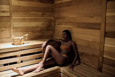 Wood-lined sauna with a guest seated on the bench at 1 Hotel Hanalei Bay.