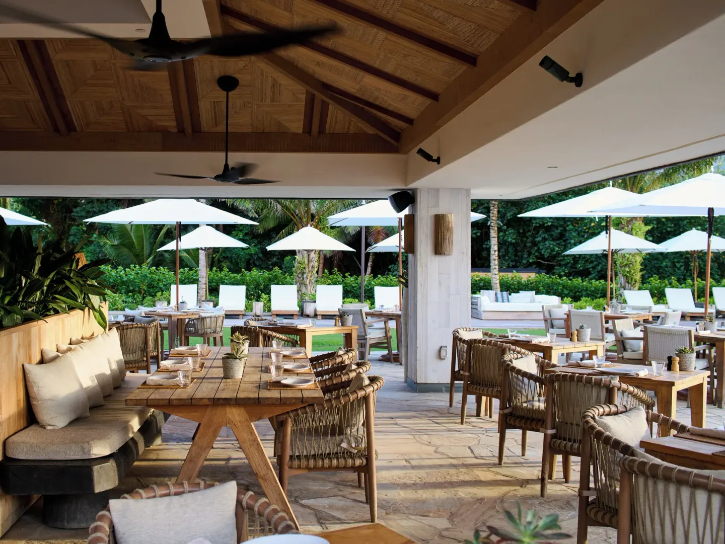 Covered outdoor dining patio with tables and umbrellas at 1 Hotel Hanalei Bay.