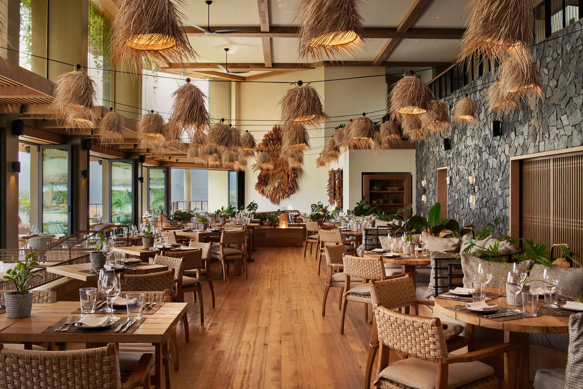 Dining room with woven chairs and thatched pendant lights at 1 Hotel Hanalei Bay.