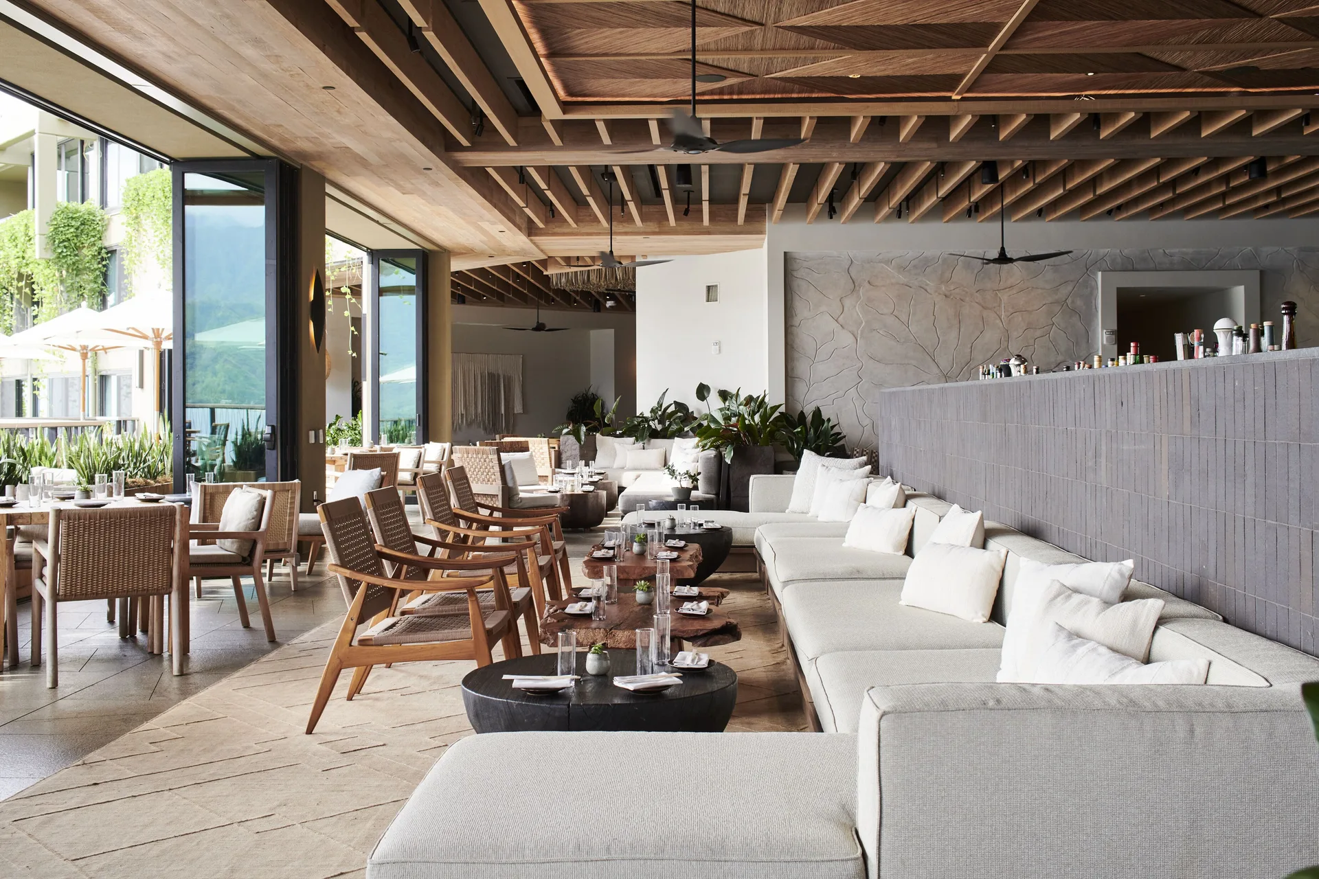 Open-air lounge seating and low dining tables at 1 Hotel Hanalei Bay.
