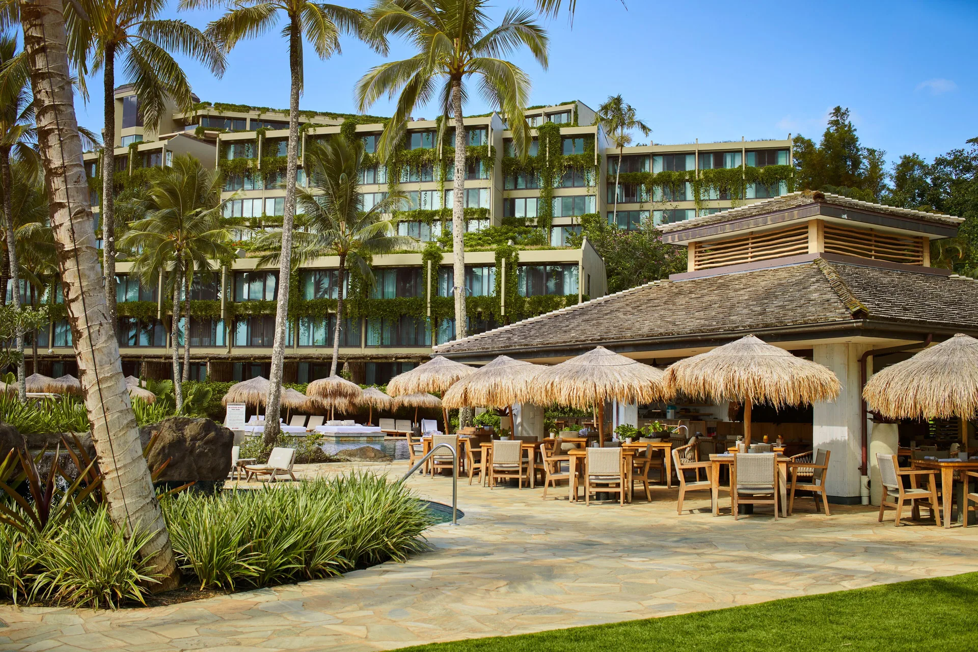 Poolside restaurant terrace with thatched umbrellas at 1 Hotel Hanalei Bay.