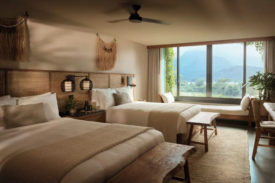 Two queen beds face a wide mountain-view window in a guest room at 1 Hotel Hanalei Bay.