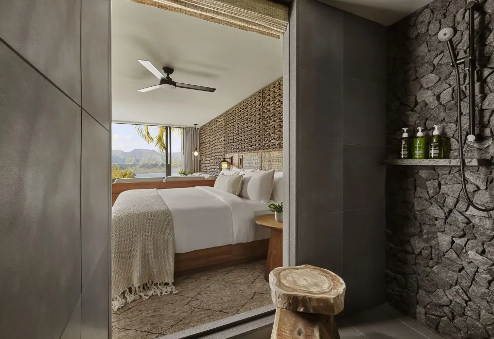 Mountain View bathroom shower with stone wall and guest room beyond at 1 Hotel Hanalei Bay.