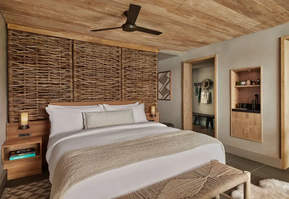 King bed with woven headboard in an Ocean View Terrace Studio Suite at 1 Hotel Hanalei Bay.