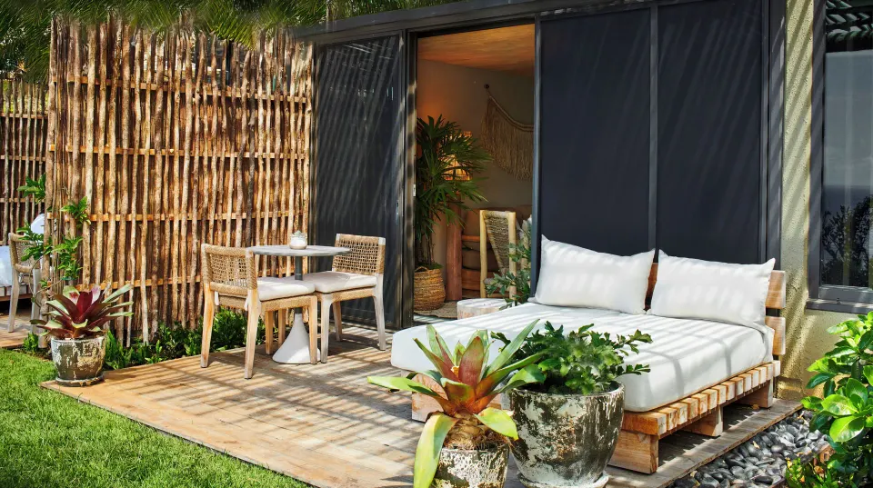 Private terrace with daybed and dining set outside a Pool View Terrace room at 1 Hotel Hanalei Bay.