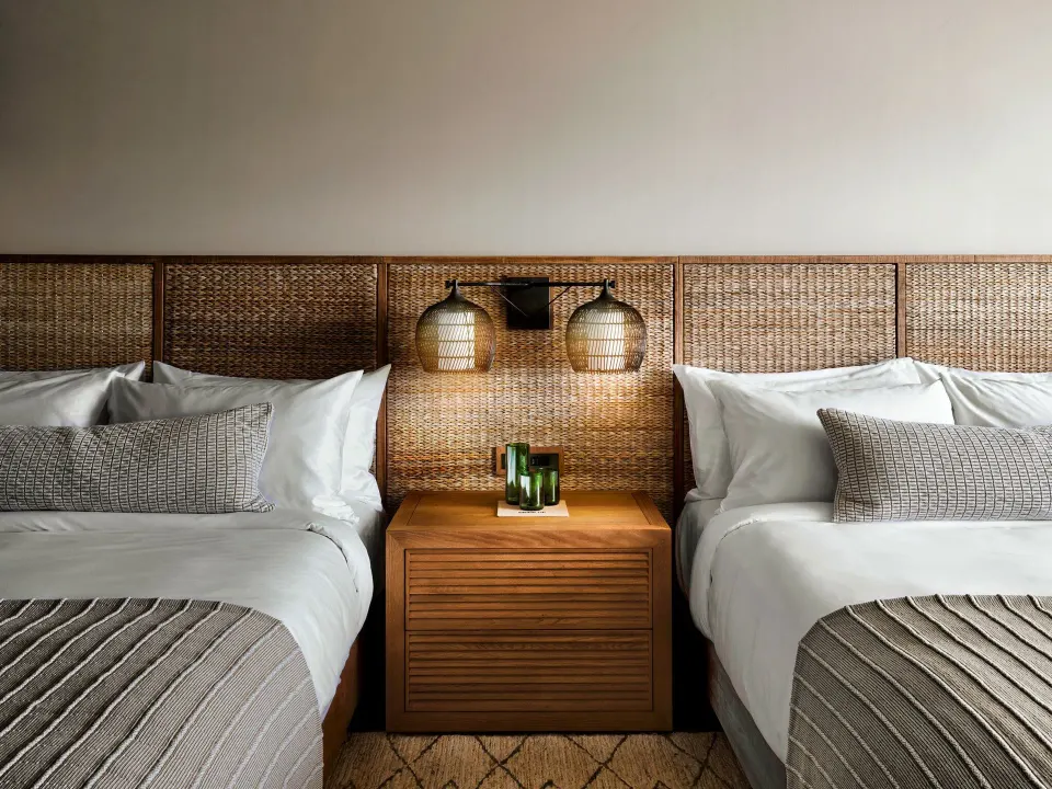 Two double beds with lit woven lamps in a Pool View Terrace room at 1 Hotel Hanalei Bay.