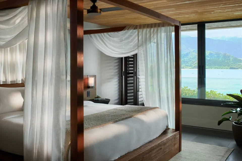 Pu'u Poa Ocean Loft Suite canopy bed with bay and mountain views at 1 Hotel Hanalei Bay.