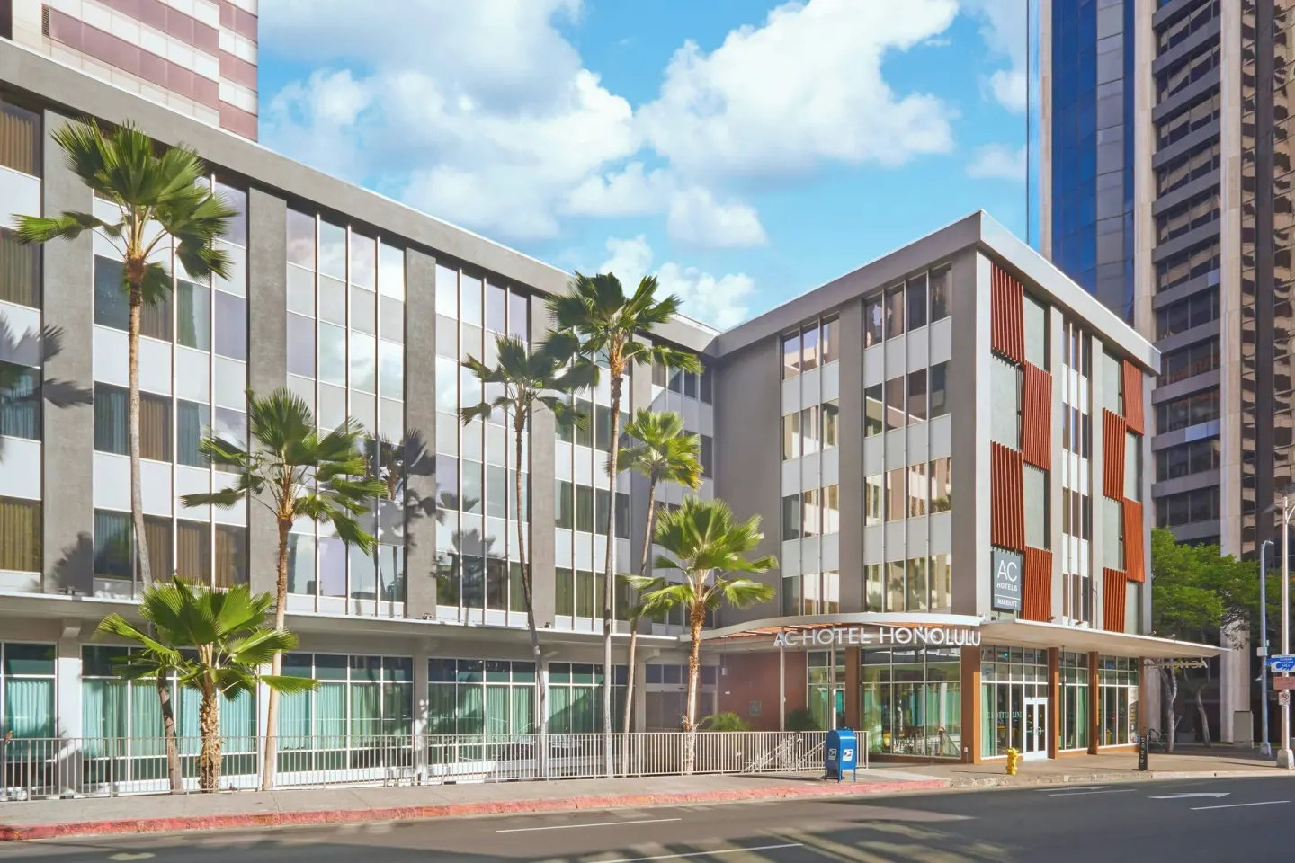 Street view of the palm-lined exterior and entrance at AC Hotel Honolulu.