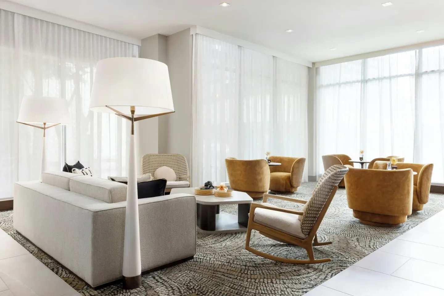 Bright lounge with sofas, armchairs, and sheer curtains at AC Hotel Honolulu.