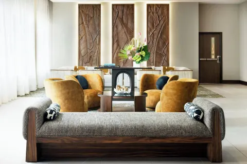 Lobby seating with lounge chairs, carved wall panels, and flowers at AC Hotel Honolulu.