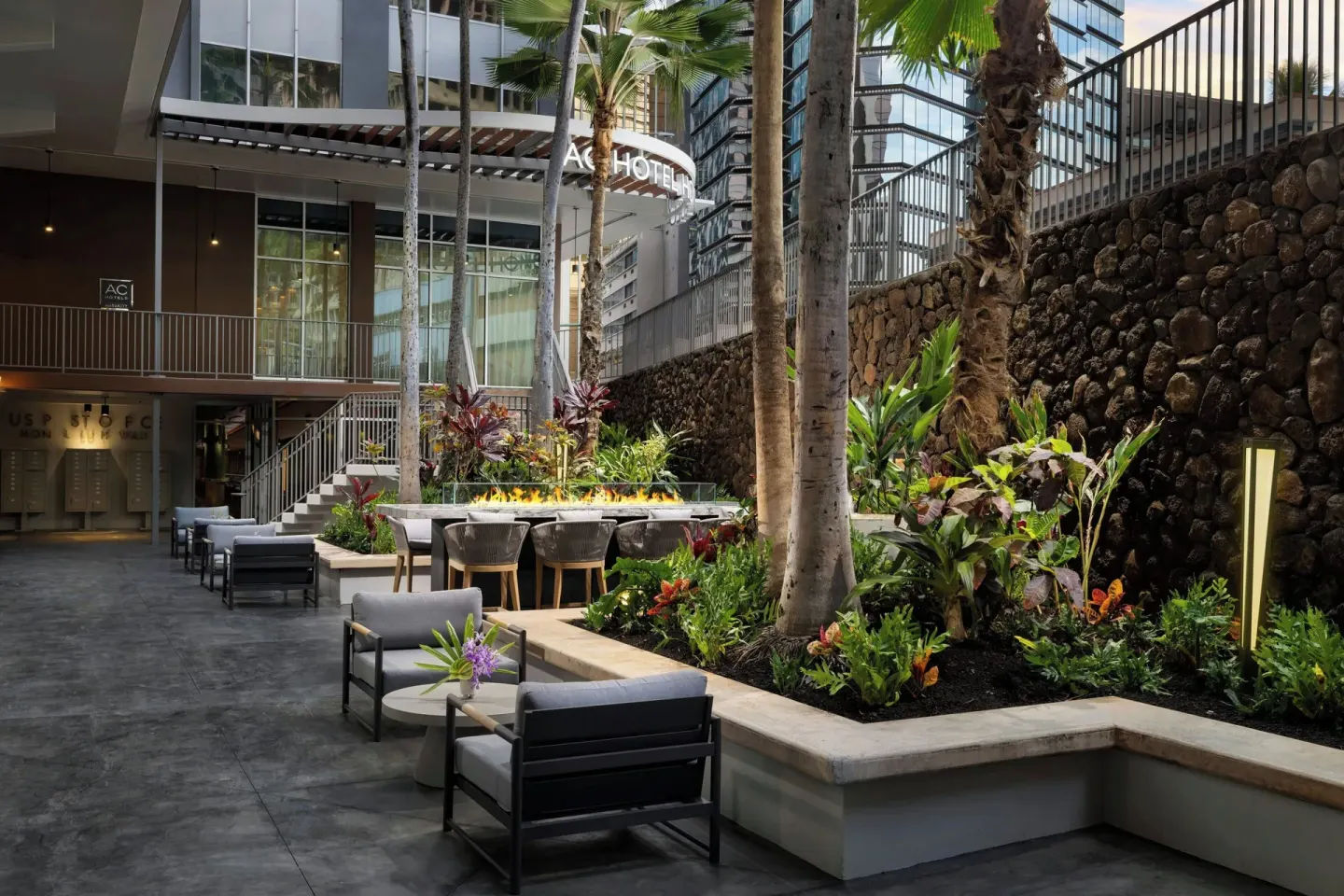 Outdoor courtyard seating with palms and a fire feature at AC Hotel Honolulu.