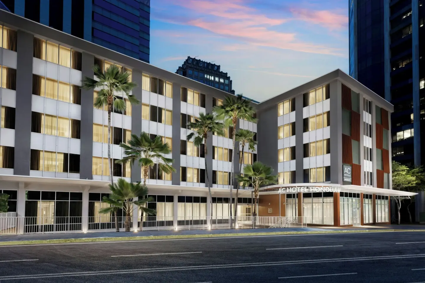 Exterior of AC Hotel Honolulu with lit windows and palm trees at twilight.