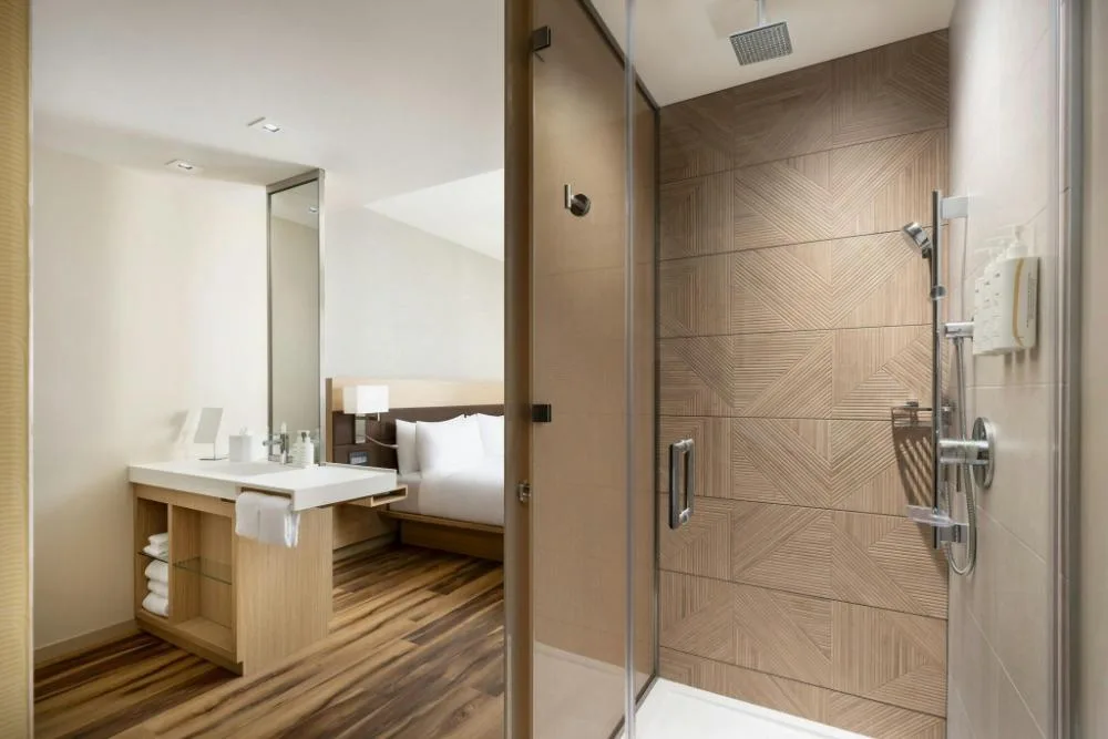 City View guest room bathroom with glass shower and vanity at AC Hotel Honolulu.