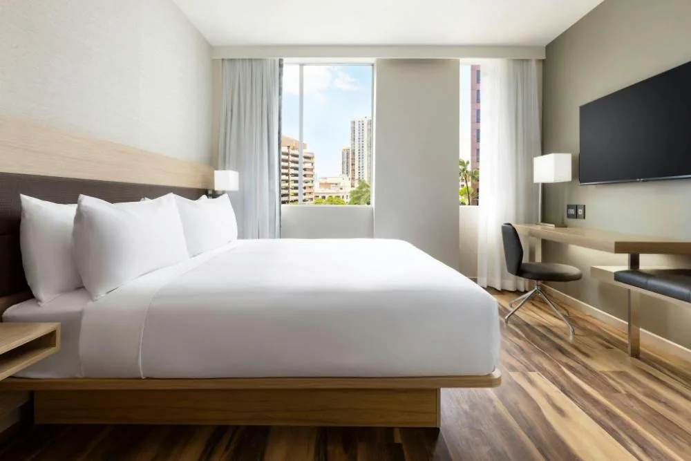 City View king room with wall-mounted TV and desk at AC Hotel Honolulu.
