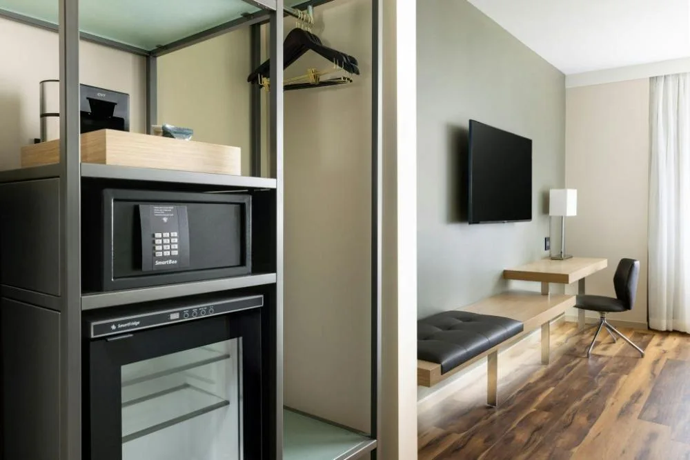 City View room closet with safe, mini fridge, desk, and TV at AC Hotel Honolulu.