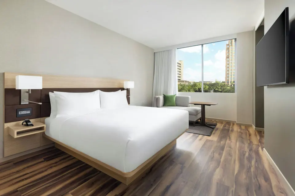 City View king room with sofa, table, TV, and large windows at AC Hotel Honolulu.