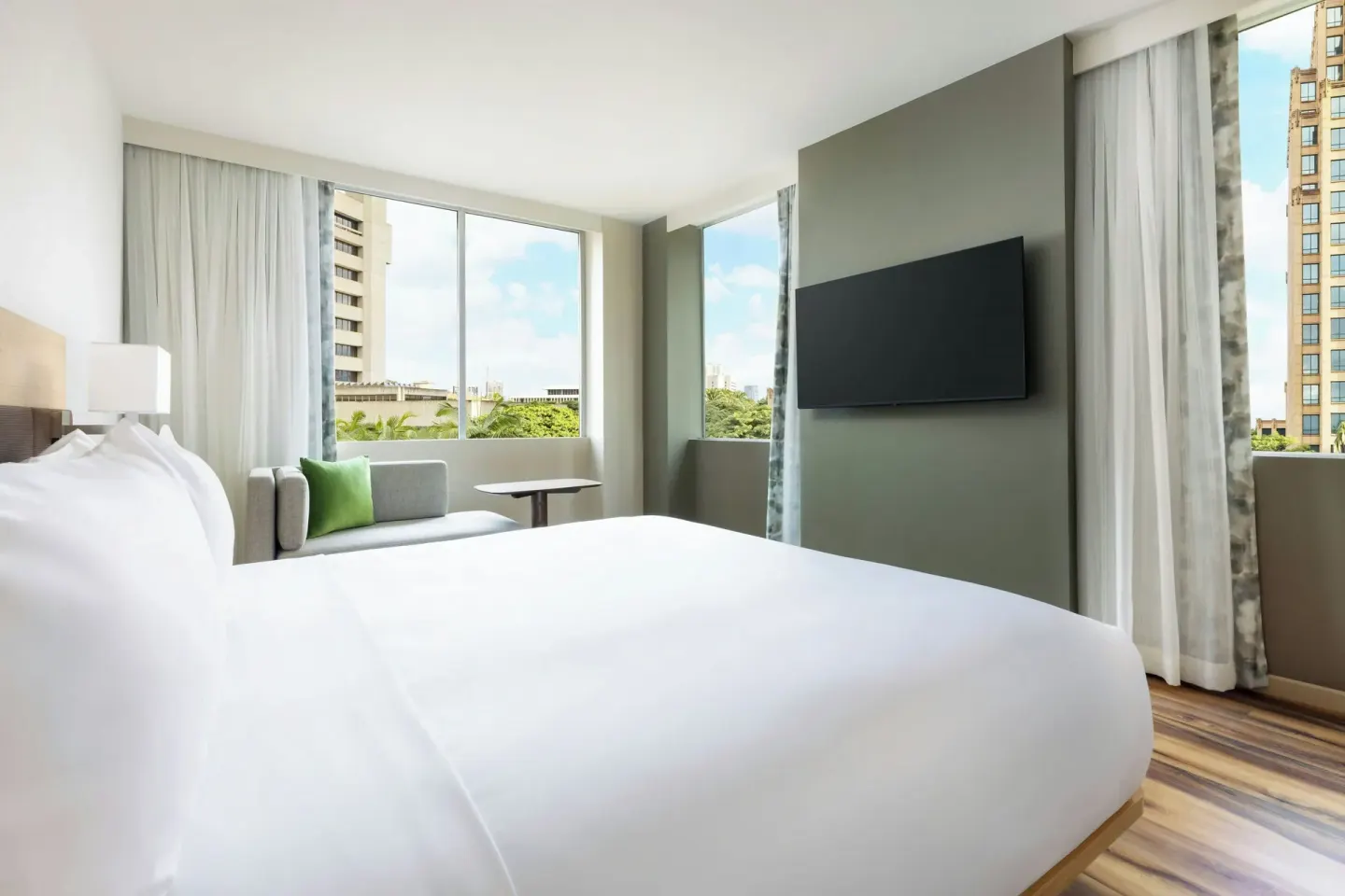 City View king room with bed, TV wall, sofa, and corner windows at AC Hotel Honolulu.