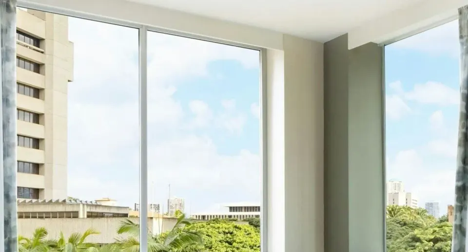 City View room windows showing nearby buildings, palm trees, and sky at AC Hotel Honolulu.