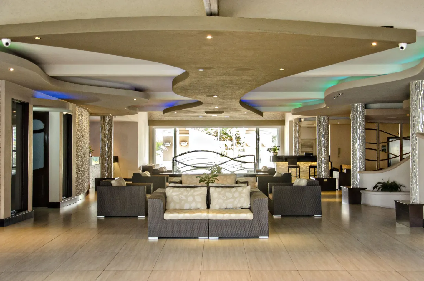 Lobby lounge with wicker seating and curved ceiling lighting at Accra Beach Hotel & Spa.