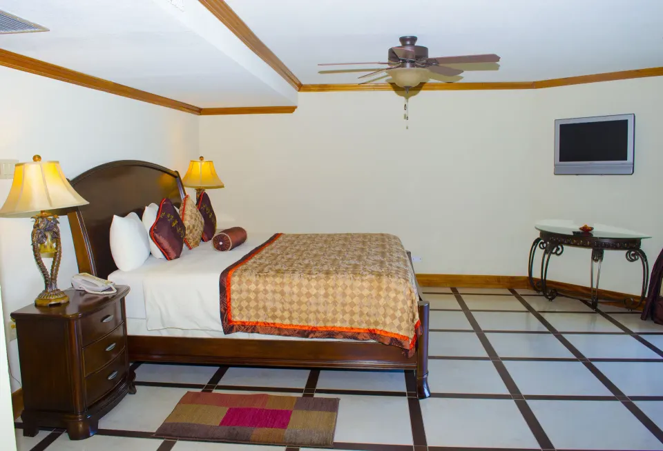 Deluxe Junior Suite bed and wall-mounted TV at Accra Beach Hotel & Spa.