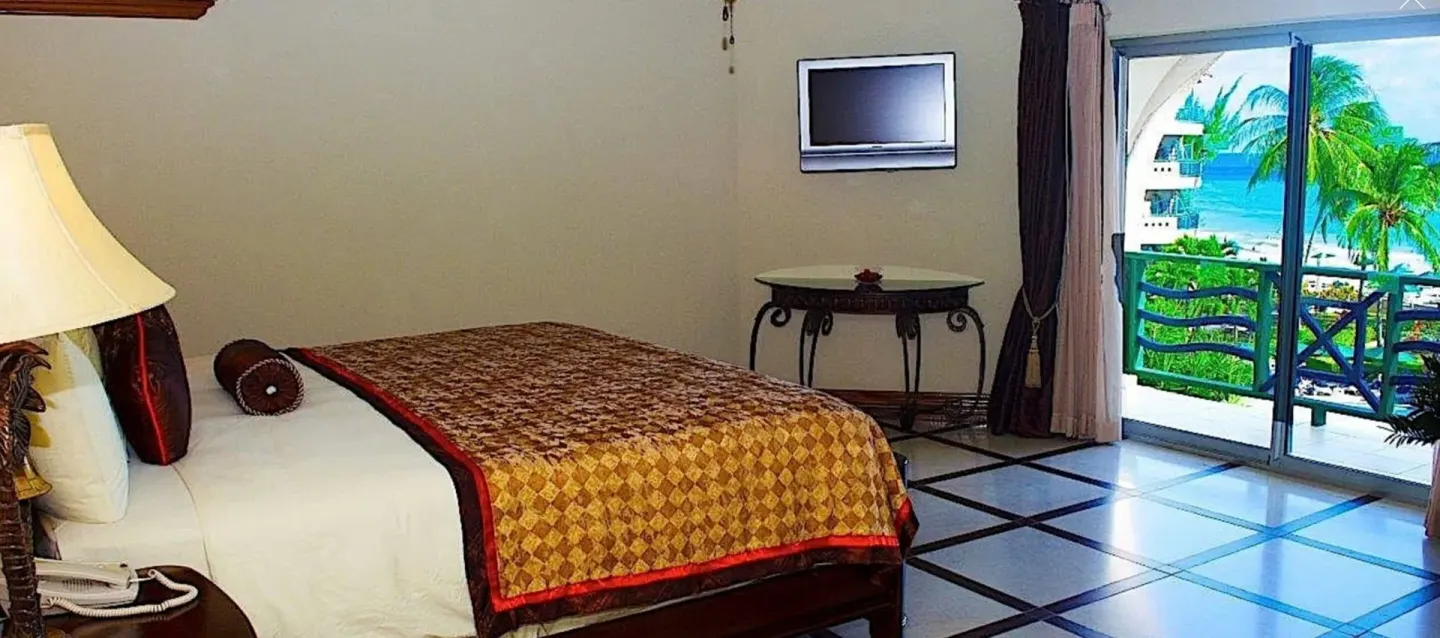 Deluxe Junior Suite bed beside balcony doors at Accra Beach Hotel & Spa.