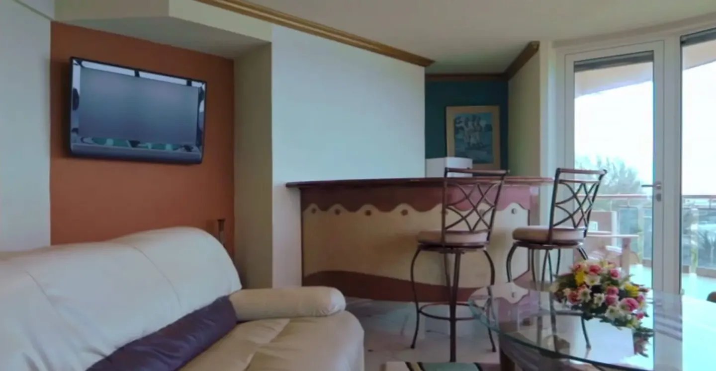 Luxury Oceanfront Suite lounge at Accra Beach Hotel & Spa with sofa, bar seating, TV, and balcony doors.