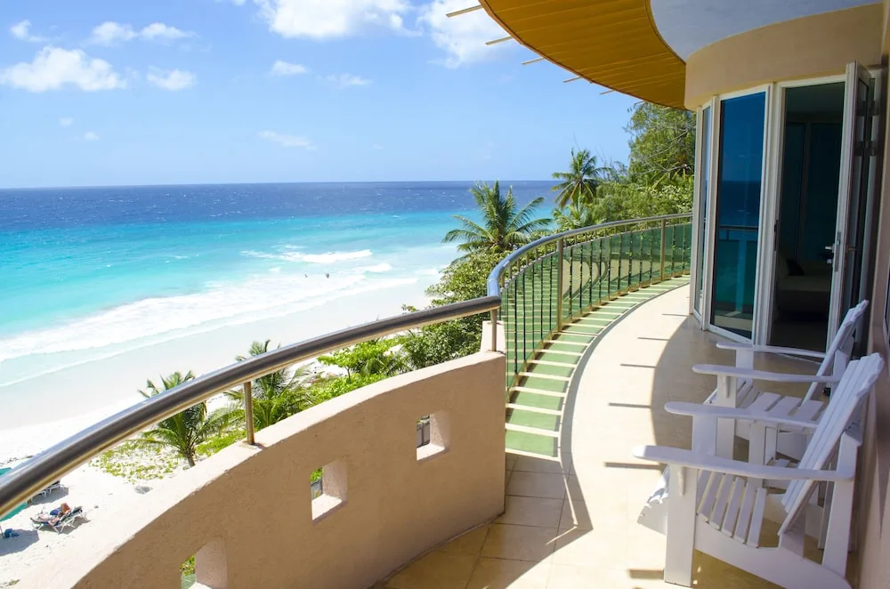 Oceanfront balcony with white chairs and beach view at Accra Beach Hotel & Spa.