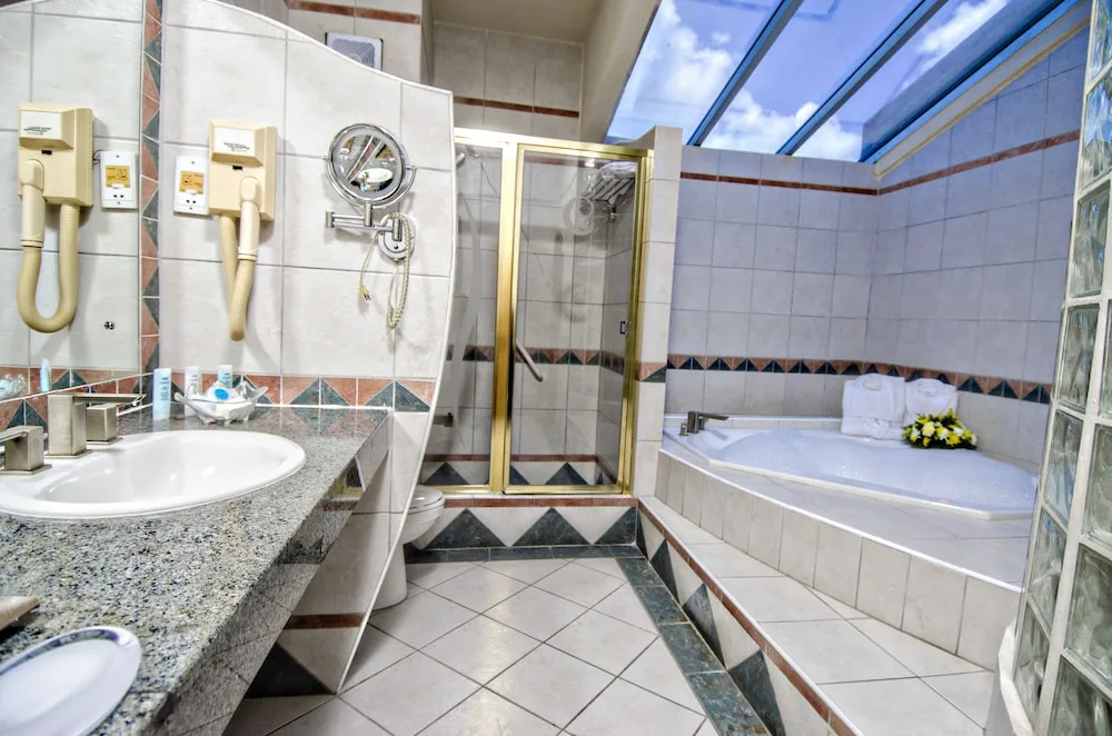 Tiled bathroom with tub, shower, vanity, and skylight at Accra Beach Hotel & Spa.