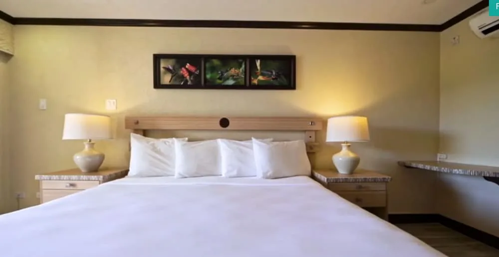 Two-bedroom pool view suite bedroom with a white bed and lamps at Accra Beach Hotel & Spa.