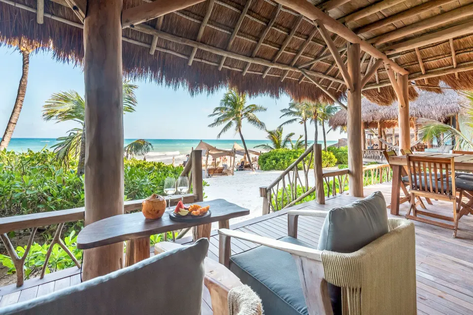 Open wooden palapa seating area with lounge chairs and sea view at Ahau Tulum.