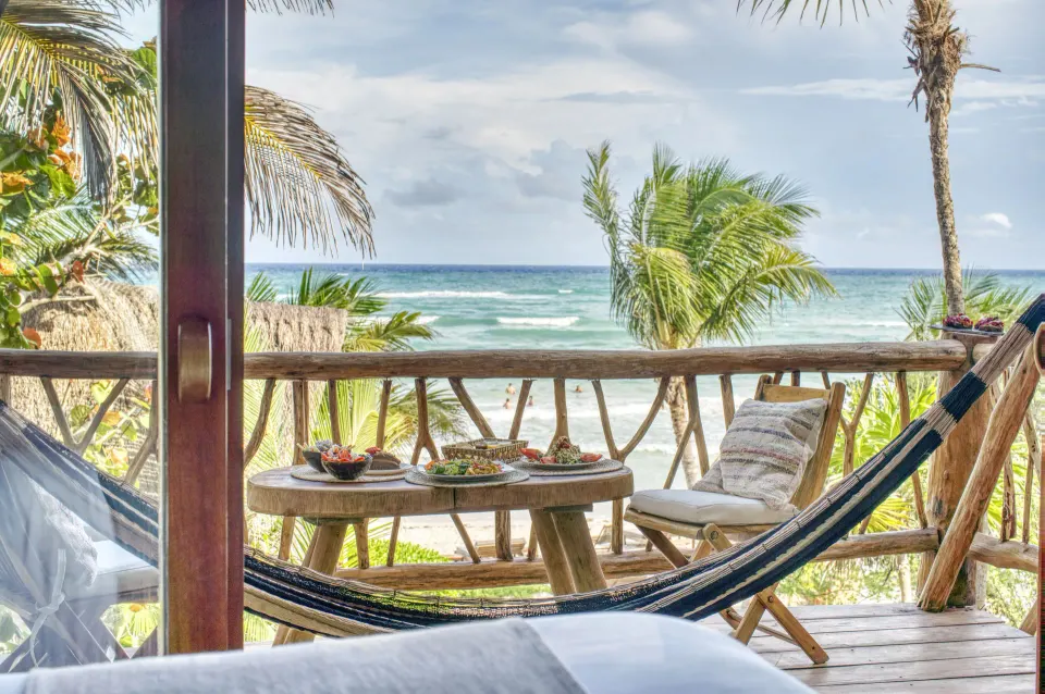 Ocean-facing terrace with seating and daybed at Ahau Tulum overlooking the beach