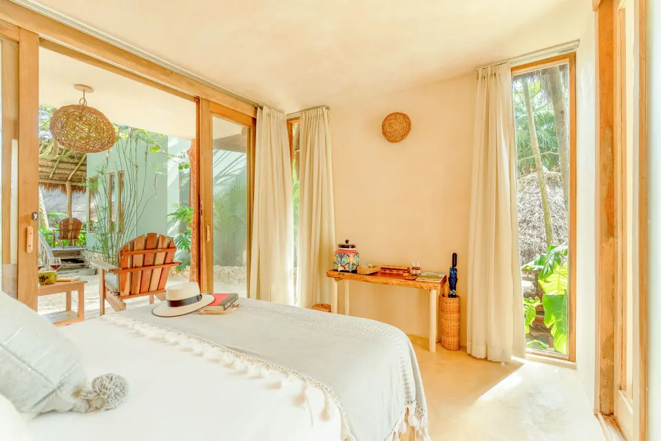 Guest room king bed looking toward a patio and garden at Ahau Tulum