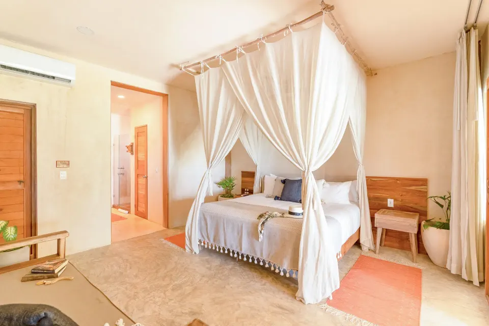 Canopy king bed and soft neutral decor in a guest room at Ahau Tulum