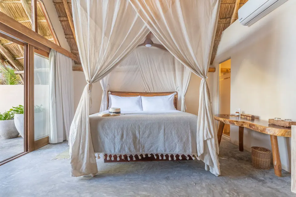 Four-poster canopy bed with white drapes in a cozy room at Ahau Tulum