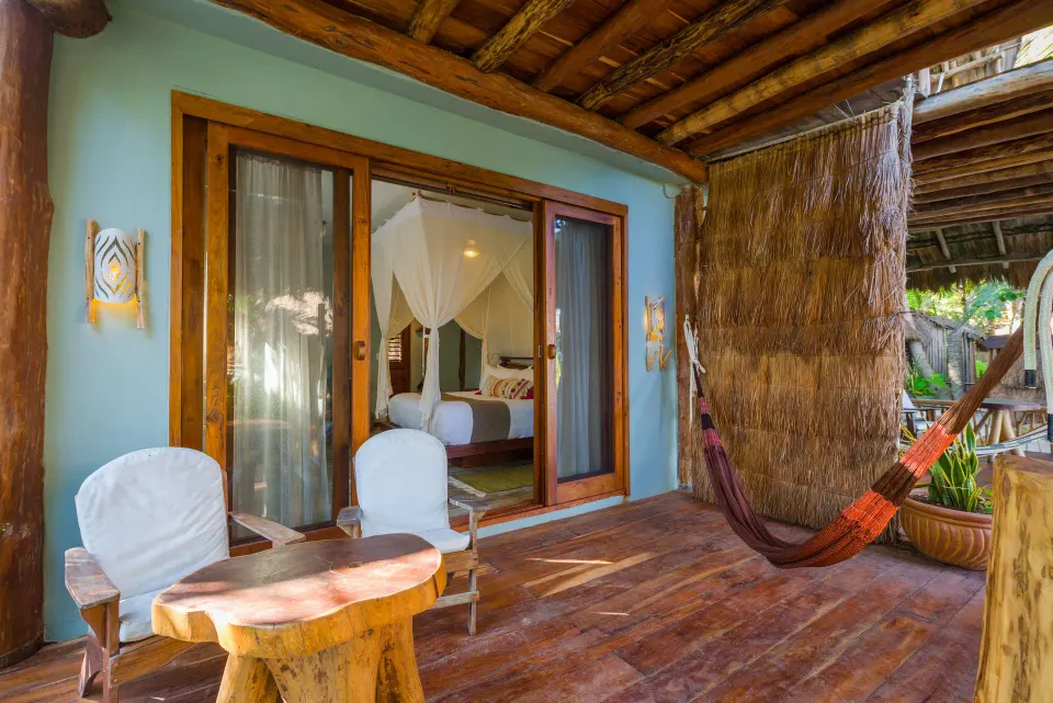 Private wooden terrace with hammock and seating outside a guest room at Ahau Tulum