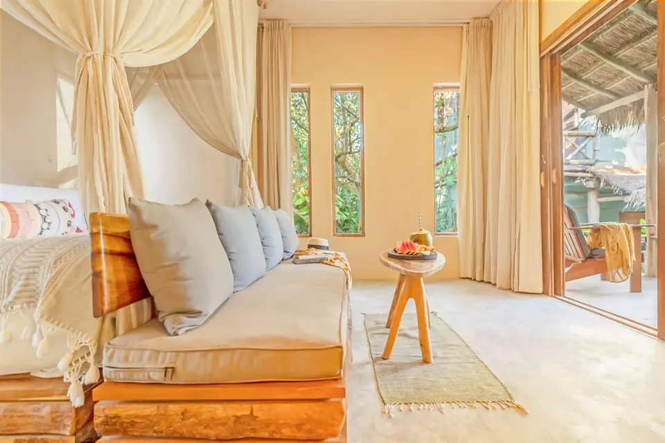 Daybed seating and light-filled doorway in a guest room at Ahau Tulum