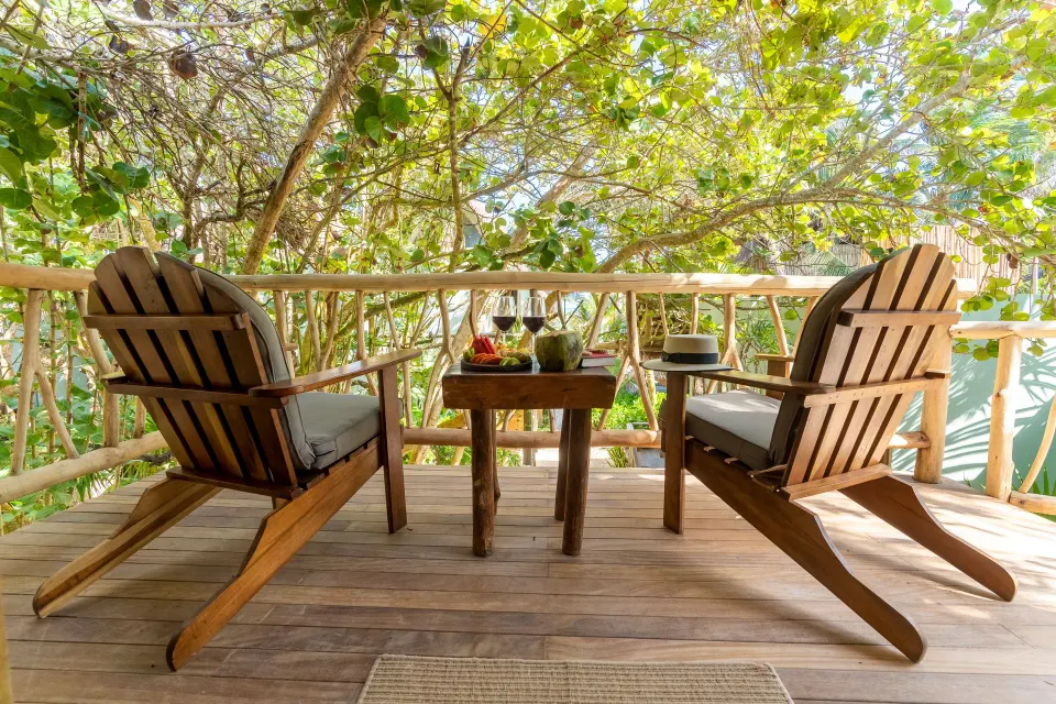 Wooden lounge chairs and small table on a private deck at Ahau Tulum.