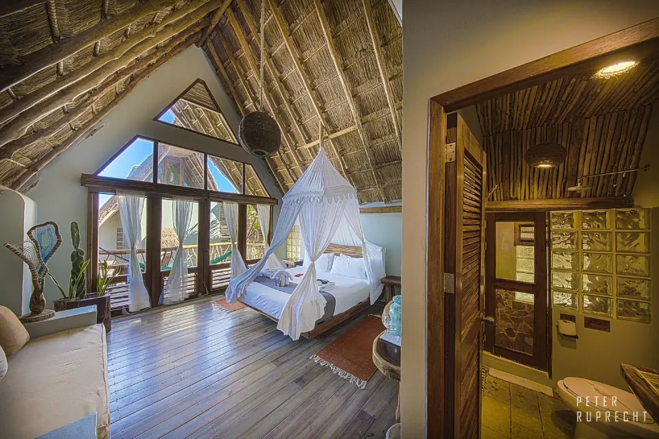 Thatched-ceiling junior suite with canopy bed and balcony at Ahau Tulum