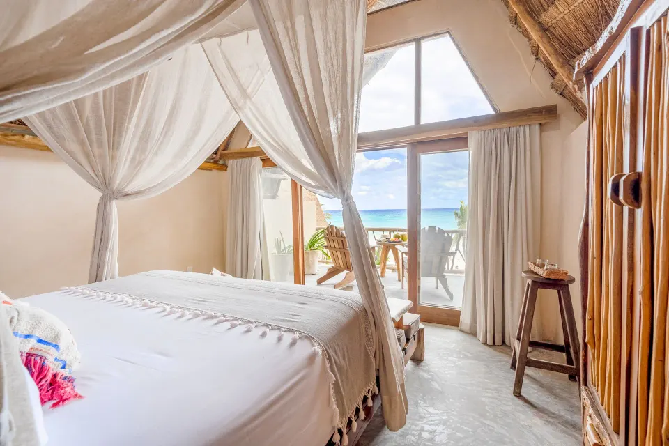 Canopy king bed looking toward a terrace and sea view at Ahau Tulum