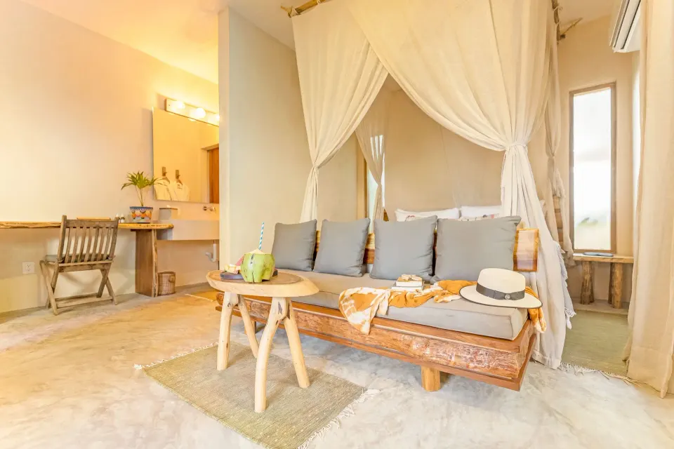 Canopy king bed with sofa and vanity area in a guest room at Ahau Tulum