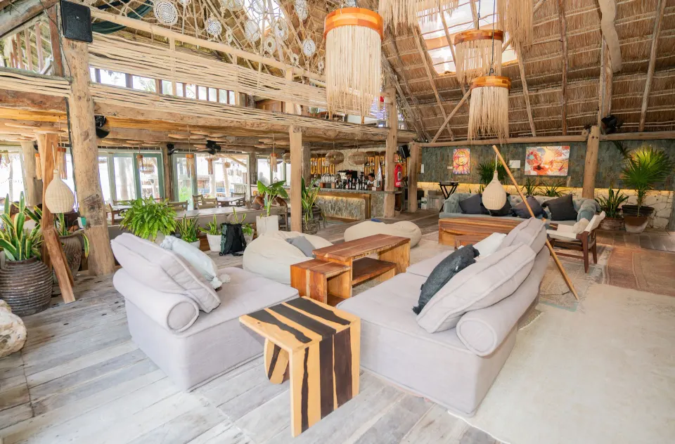 Lounge seating and bar area beneath a palapa roof at Ahau Tulum