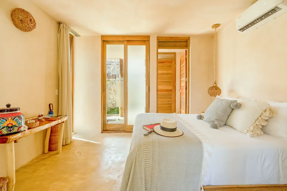 Minimalist king bed with natural light from narrow windows at Ahau Tulum