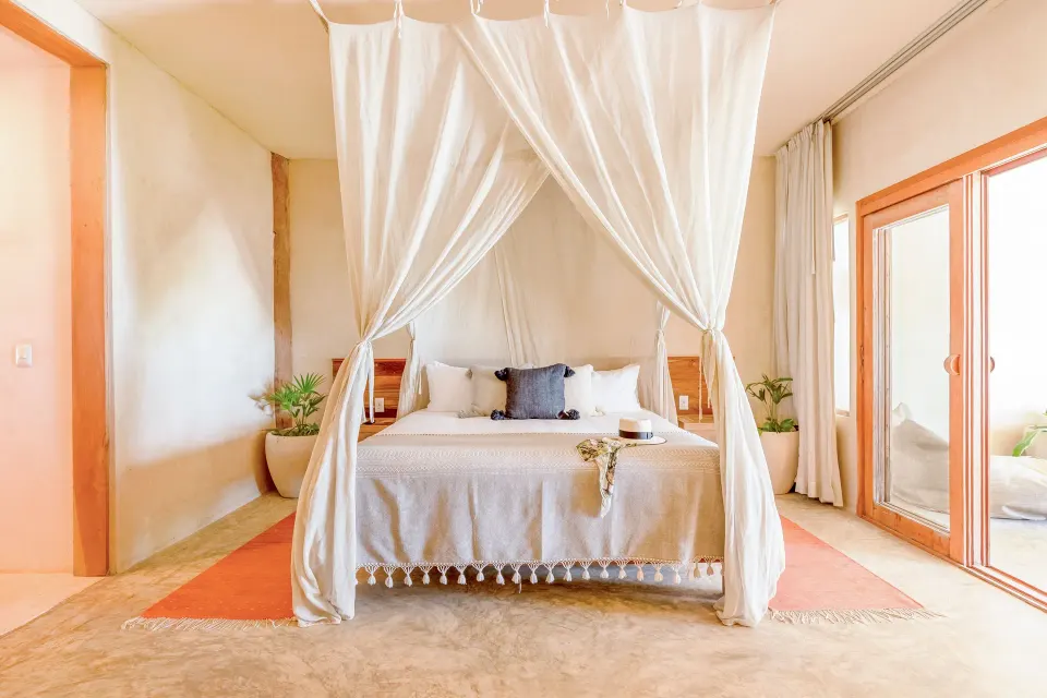 Minimalist suite with canopy bed and sliding doors at Ahau Tulum