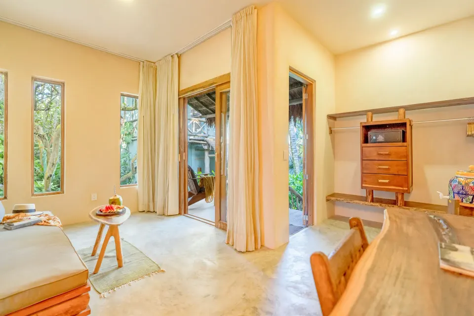 Open-plan guest room showing seating area and storage alcove at Ahau Tulum