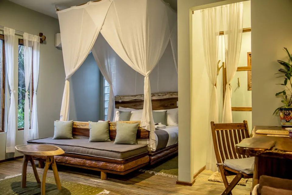 Open-plan suite with canopy bed and daybed seating at Ahau Tulum