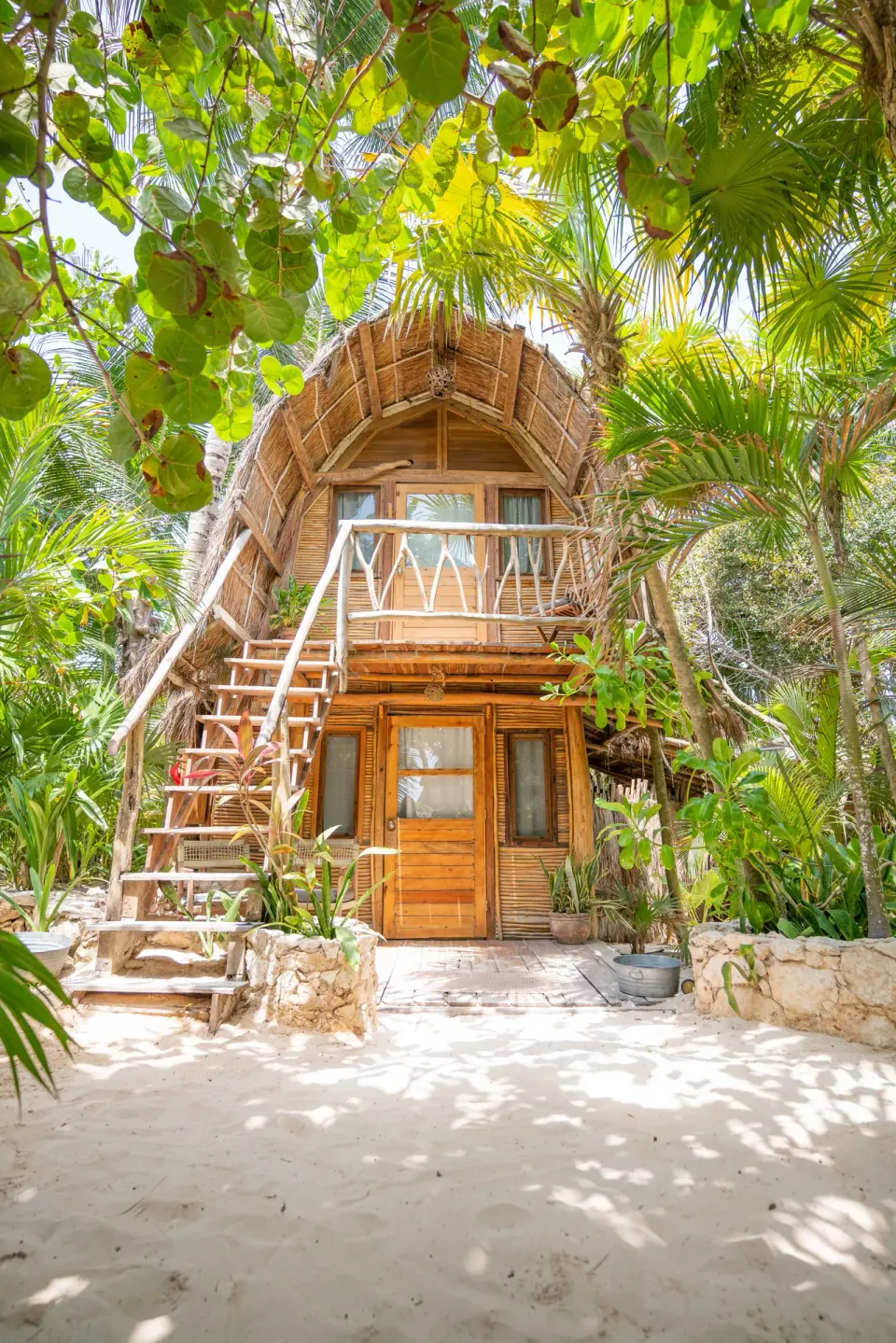 Two-story palapa bungalow exterior surrounded by tropical foliage at Ahau Tulum