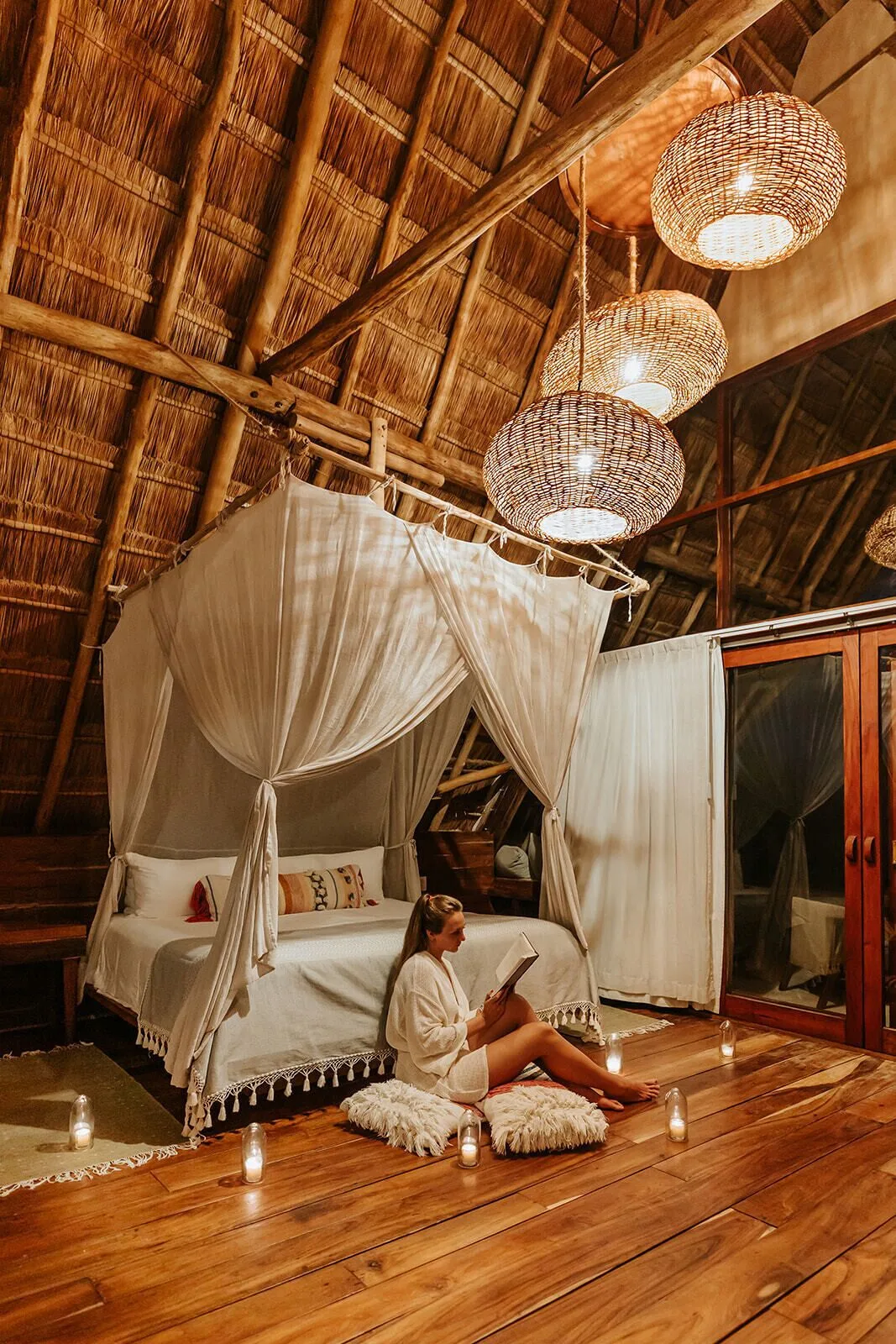 Thatched-roof loft bedroom with canopy bed and candles at Ahau Tulum