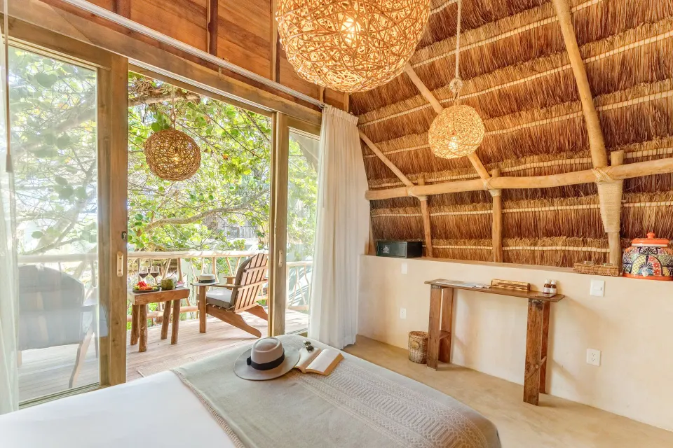 Bright palapa guest room with king bed and balcony at Ahau Tulum