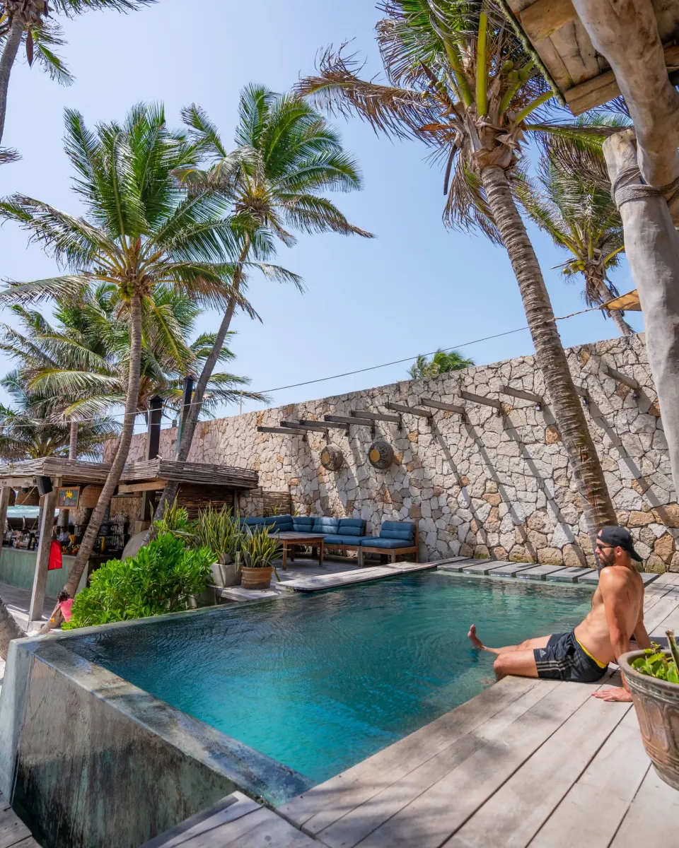 Small rectangular pool beside stone wall and palm trees at Ahau Tulum